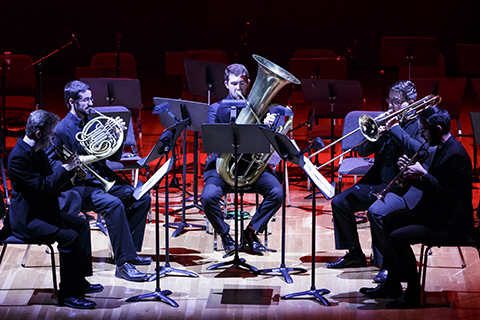 A group of brass players in suits perform on stage
